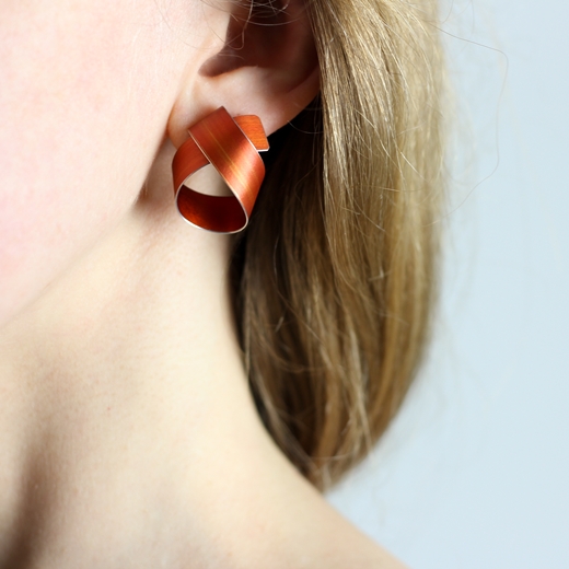 Orange wide coil stud earrings worn
