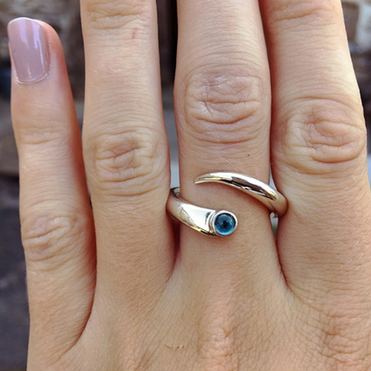 Curving silver ring with blue topaz