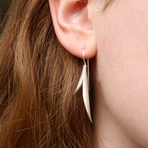 Long curved seed pod earring on model